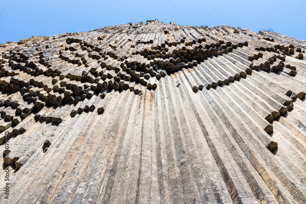 Poster symphony of the stones - bottom view of surface natural basalt columns in Garni gorge in Armenia on sunny autumn day