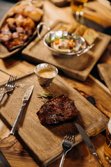 Fresh juicy delicious beef steak on wooden background in restaurant. Meat dish with spices and herbs