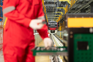 Picture of engineer using repair tools of the electric train industry There is an electric train in the train repair factory as the background image.