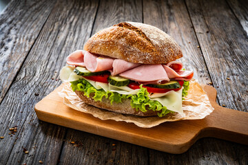 Sandwich with mortadella pistachios, tapenade and cheese on wooden table
