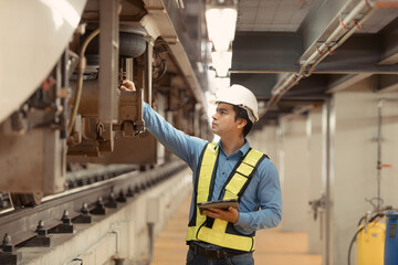 Electric train engineer inspect electric train machinery with tablets according to inspection round after the electric train is parked in the electric train's repair shop
