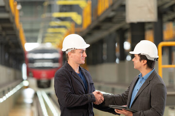 Two businessmen shaking hands after reaching an agreement to reserve equipment for use in repairing tracks and machinery of the electric train transportation system.