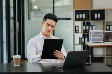 Young attractive Asian male office worker business suits smiling at camera in office
