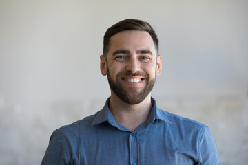 Happy handsome Caucasian man in casual blue shirt looking at camera, smiling, laughing. Cheerful millennial business professional, businessman, small company owner, leader indoor head shot portrait