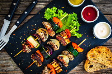 Meat skewers - grilled meat with vegetables on wooden background