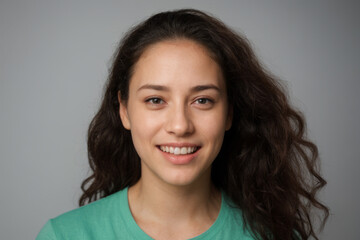 Fototapeta premium Everyday people. A smiling European student. Brown wavy hair over her shoulder. Wearing a white sleeveless shirt. On a light studio background. Portrait. 
