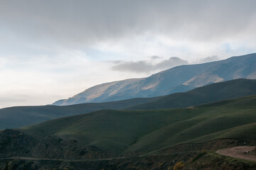 Obraz premium Sunset view of green grass-covered hills and mountains of Kazakhstan near Assy plateau in autumn