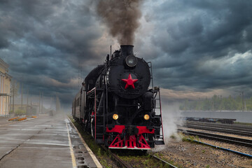 An old steam locomotive of the early 20th century on the railway track.