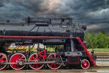 An old steam locomotive of the early 20th century on the railway track.