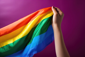 A woman's hand holding an lgbt flag on a burgundy background