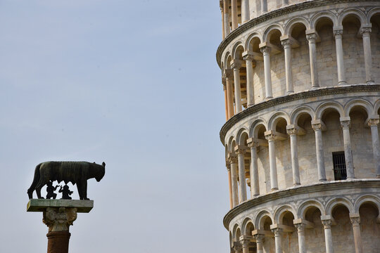 Pisa, Italy. September 16, 2023. Statue of Romulus and Remus suckling the she wolf Capitolina in front of a section of the Leaning Tower.
