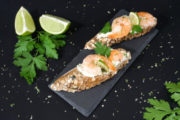 Crispy appetizer with wholemeal bread, spreadable cheese, shrimp and lime