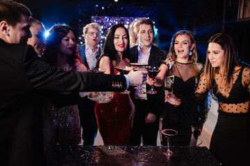 happy group of friends celebrating new years eve party dancing throwing confetti enjoying glamorous...