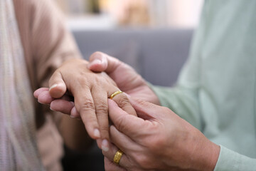 Close up view of old 60s man put wedding engagement ring on beloved woman hand finger, mature 50s...