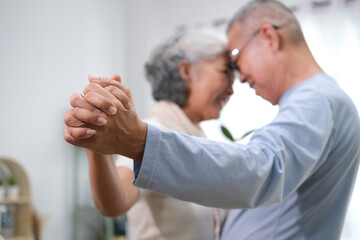 Selective focus of senior couple holding hands while dancing in living room