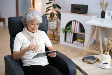 Smiling middle-aged Caucasian woman sit on couch in living room browsing wireless Internet on tablet