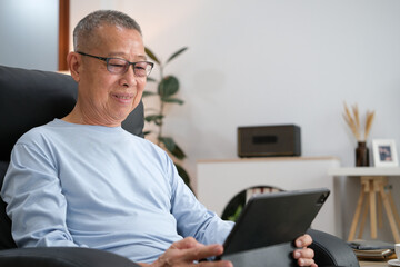 Senior Asian men at the sofa couch using smartphone tablet for browsing internet and reading news...