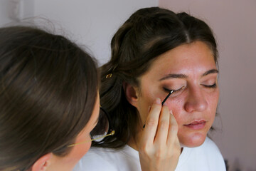 Close up of a make up artist doing bridal makeup on beautiful caucasian woman with brunette hair