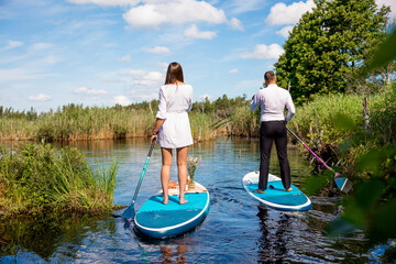 Young attractive couple on stand up paddle board in the lake, SUP