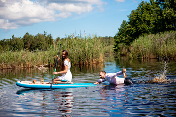 Beautiful woman and man have fun on sup, Inflatable stand up paddle board