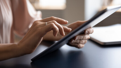 Close up arm businesswoman holds tablet computer working using internet business app seated at...