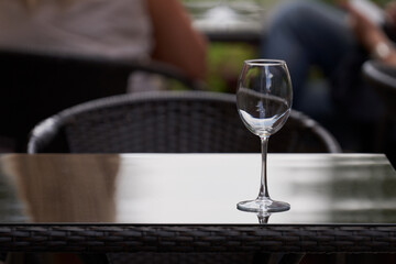Wine tasting from the winery. A table with a lonely flute from which the wine is drunk. The background with people is blurred.