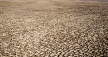 The aerial shot highlights the textured pattern of a plowed farm field against the solid black soil.