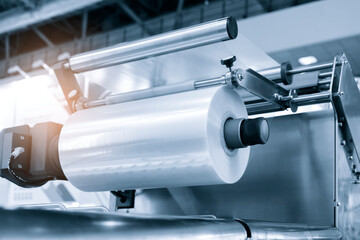 Automatic polyethylene plastic bag production machine with lighting effect. Close-up of the roller of the plastic bag production machine in the light blue scene. product packaging concept