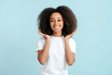 Happy authentic african american woman with curly hair wearing white t shirt looking at camera