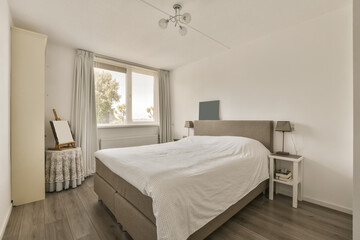 Fototapeta na wymiar a bedroom with wood flooring and white walls, including a large bed in the room has a ceiling fan