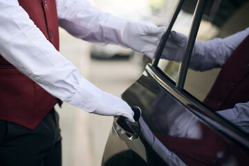 Close-up of doorman opening the door of the car and meeting the guest