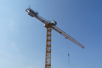 Industrial crane on a construction site against a blue sky.