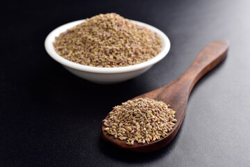 Ajwain seeds in spoon and bowl on black background
