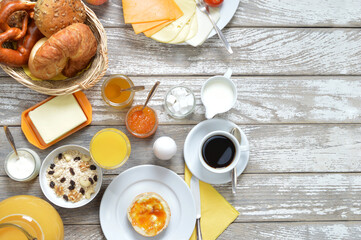breakfast table with lots of fresh food like coffee, rolls, cheese, sausages, eggs, orange juice,...