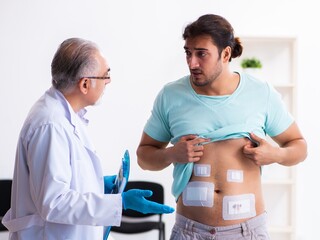 Obraz premium Injured young man visiting experienced male doctor