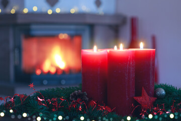 Four Advent candles on blurred fireplace background.