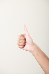 Female hand thumbs up hand gesture on grey background