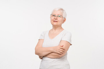 Healthy white hair elderly Caucasian woman with arms crossed studio shot portrait in white...
