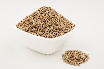 Cumin seeds in bowl on white background