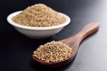 Closeup of carom seeds in spoon on dark background