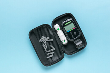 A blood glucose meter with a set of tests in a case on a blue background. The concept of getting rid of diseases. - obrazy, fototapety, plakaty