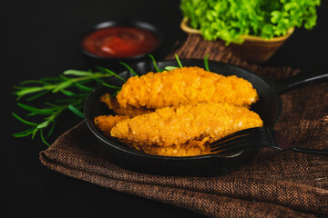Quick cooking at home.Chicken Breaded Raw Meat.Fast food.Fast cooking.Chicken nuggets with salad.Semifinished Breaded chicken nuggets from chicken fillet on a dark background with fresh herbs.