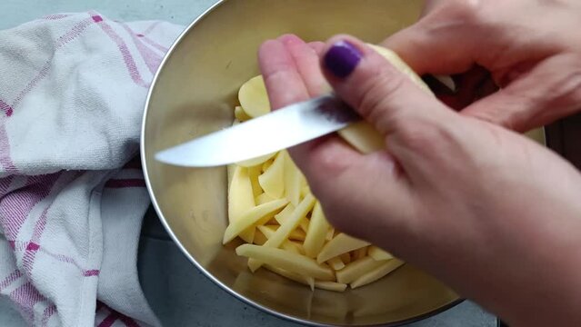 gros plan sur les mains d'une femme en train de pr&eacute;parer des frites fra&icirc;ches
