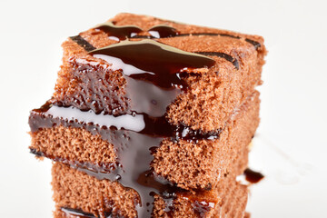 Piece of chocolate cake dripping with chocolate syrup isolated on white background