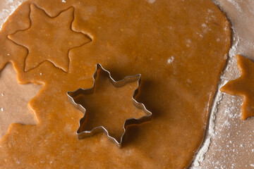 metal mold for gingerbread on dough, flour and baking paper.