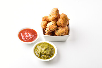 Dal pakora served with red and green chutney on white background