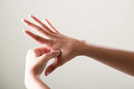 Female hand acupressure pressing palm pain on grey background