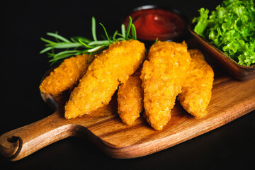 Quick cooking at home.Chicken Breaded Raw Meat.Fast food.Fast cooking.Chicken nuggets with salad.Semifinished Breaded chicken nuggets from chicken fillet on a dark background with fresh herbs.