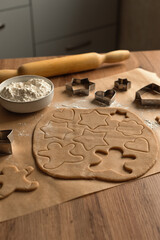 Holiday concept. Home baking concept.
Step by step process for making homemade cookies. A layer of dough with New Year's themed cookie figures on a wooden kitchen table.