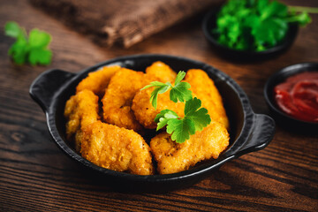 Breaded chicken nuggets. Semifinished chicken nuggets from chicken fillet on a dark background with fresh herbs. Quick cooking at home. Fast food. Breaded Chicken Inner Fillet.